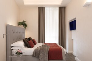 A modern bedroom with a large bed, a bedside table with a vase, and a TV mounted on the wall.
