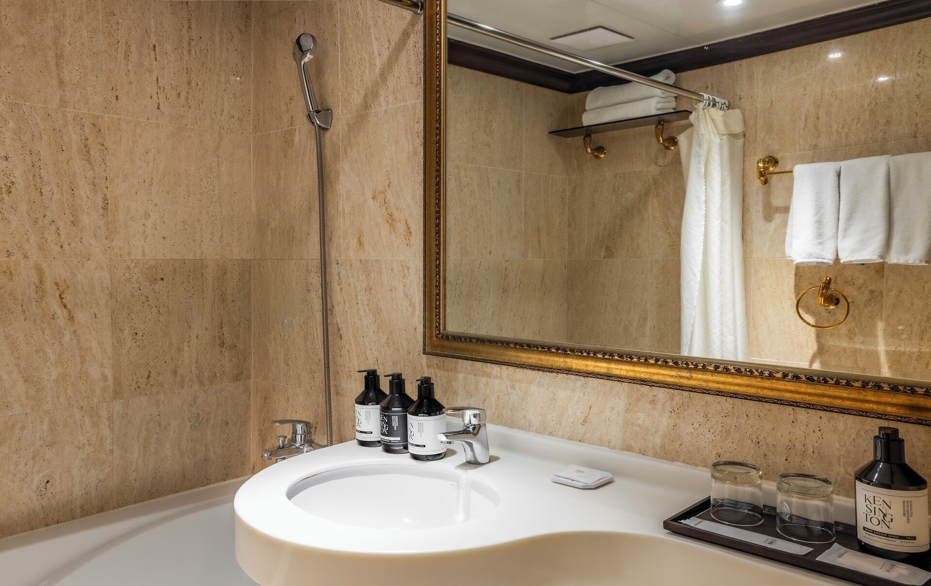 A bathroom with a large mirror, a sink with toiletries, and a shower.