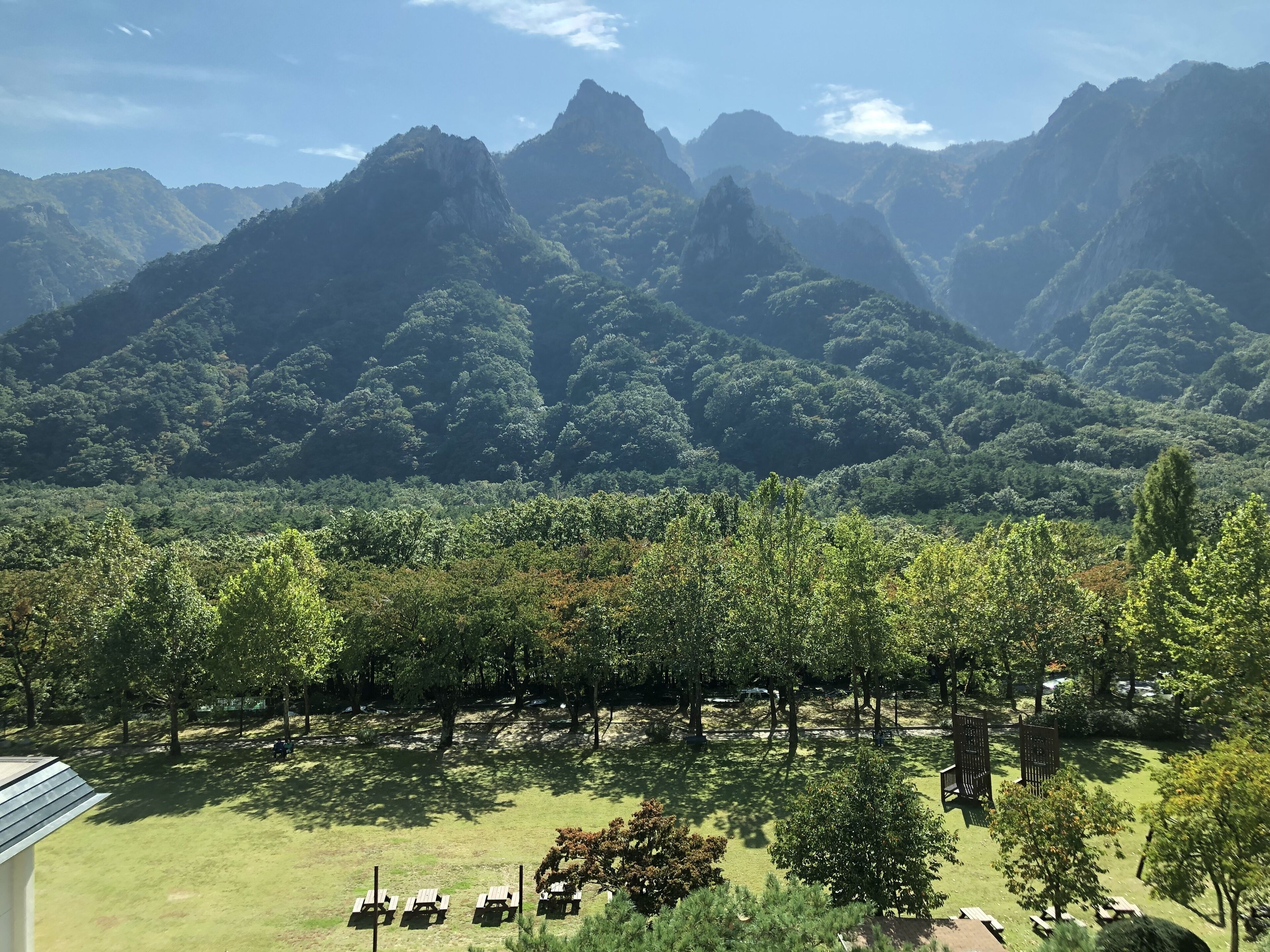 A view of a mountainous landscape with a park area featuring picnic tables and benches.