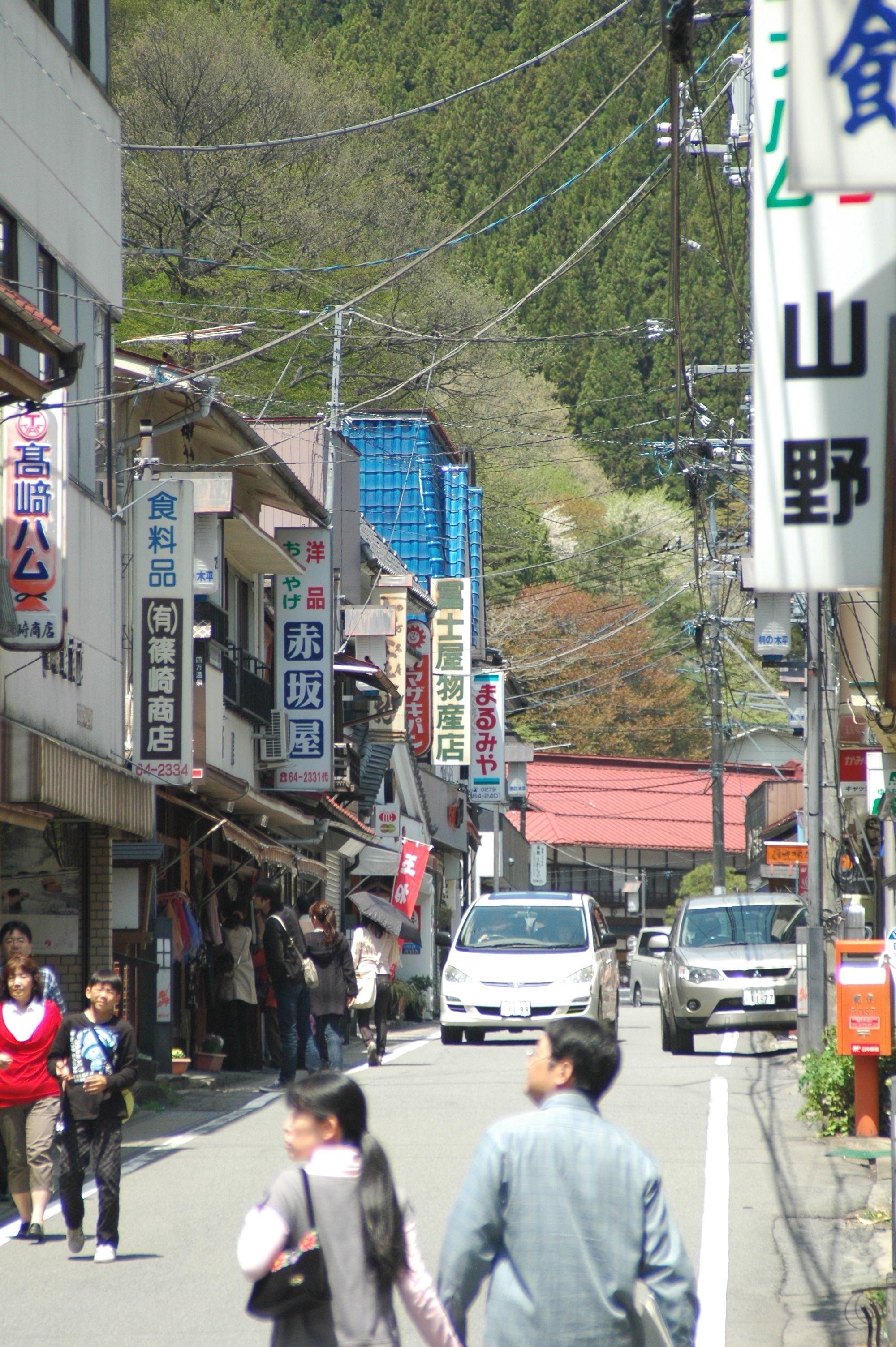A street scene with pedestrians, cars, and various commercial buildings.