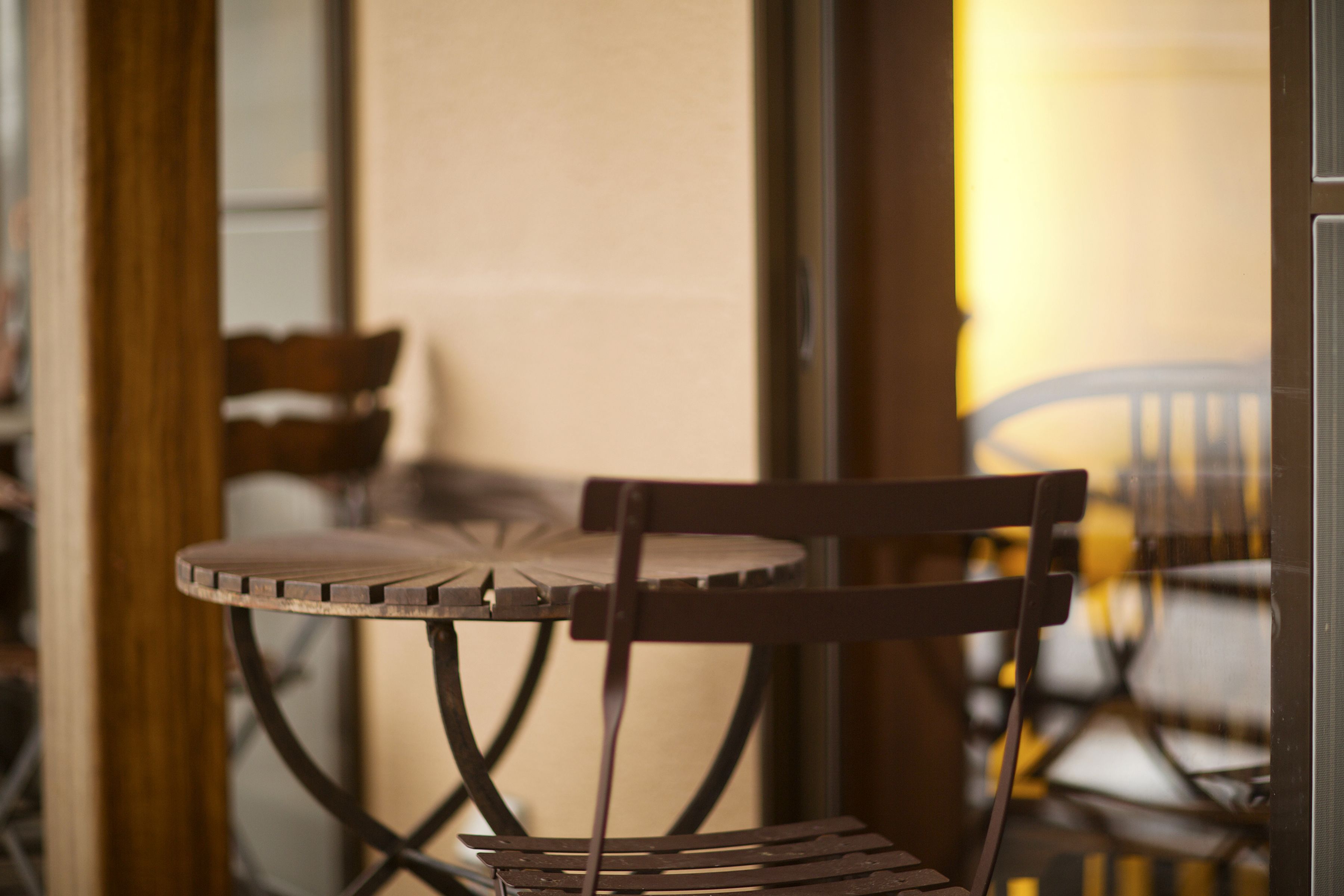 A close-up of a wooden chair with a metal frame, positioned next to a table with a round top and a metal base.