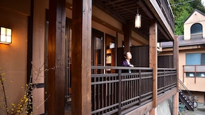 A traditional Japanese building with a wooden balcony, a potted plant, and a bicycle parked outside.