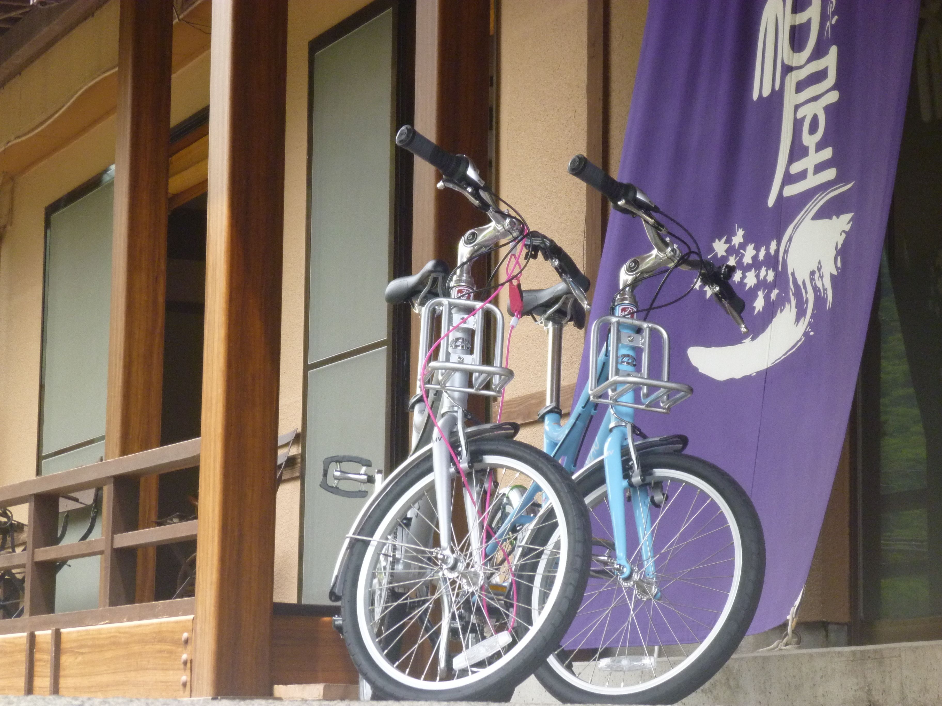 Duas bicicletas estacionadas em frente a um edifício com uma faixa roxa.