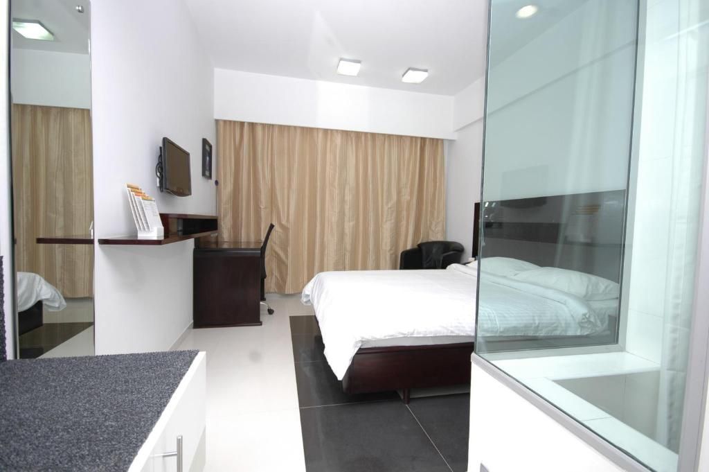 Ein modernes Hotelzimmer mit einem Bett, einem Schreibtisch, einem Stuhl, einem Fernseher und einer Glastrennwand.