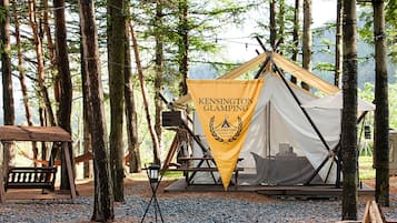 Un campamento de lujo con una tienda de campaña, un banco de madera y una bandera.