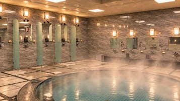 A modern spa with a hot tub, marble walls, and multiple mirrors.