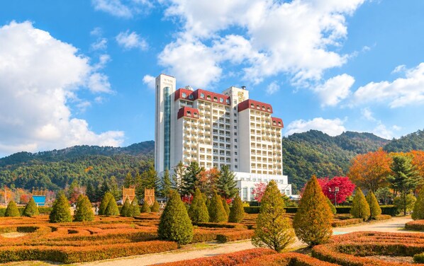 Un hôtel à plusieurs étages doté d’une cour intérieure, entouré de jardins bien entretenus et ayant une chaîne de montagnes en toile de fond.
