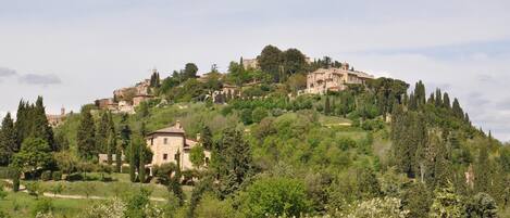 A hillside villa with multiple buildings, surrounded by lush greenery and trees.