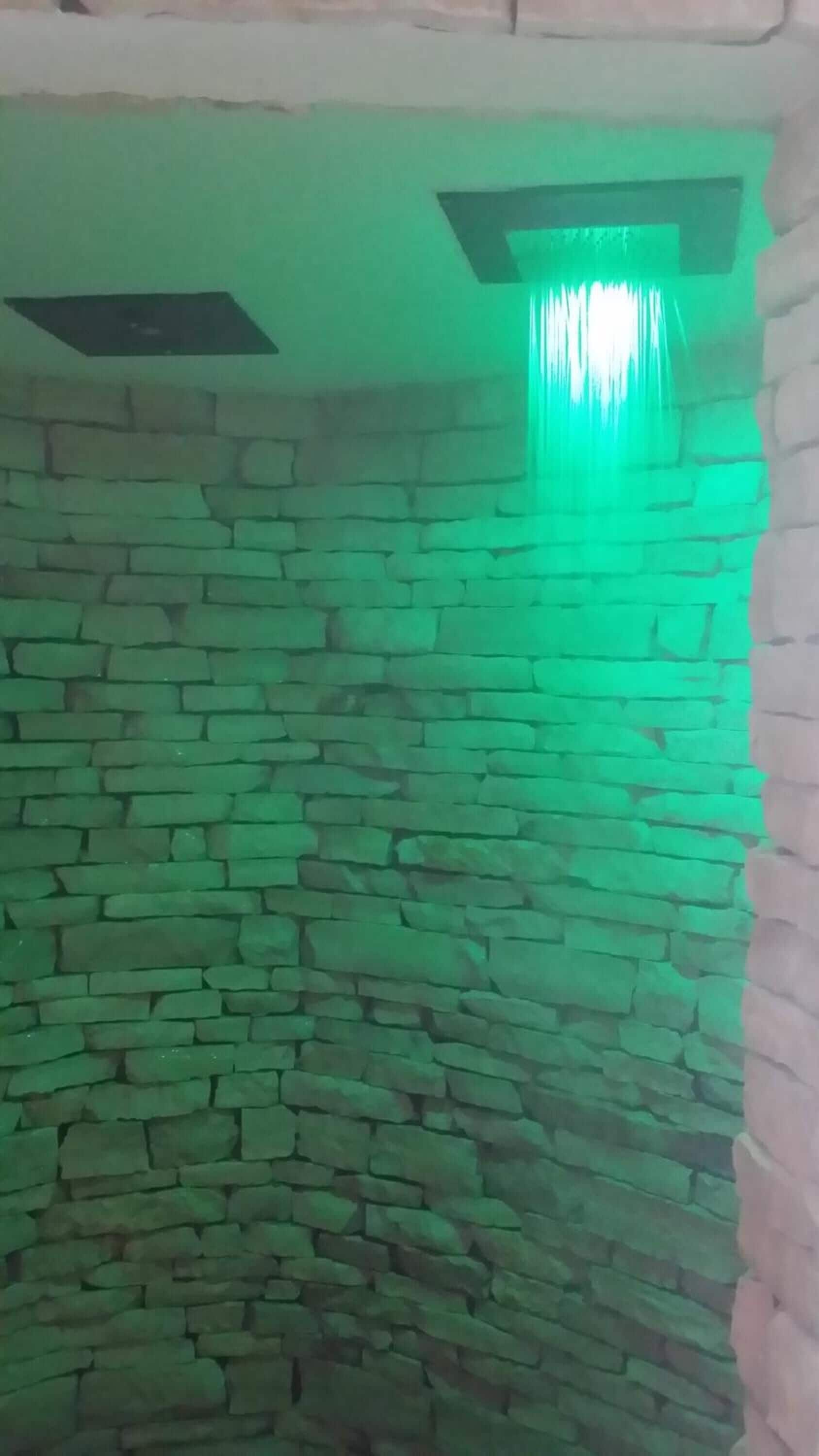 Una habitación con pared de piedra y una lámpara verde.