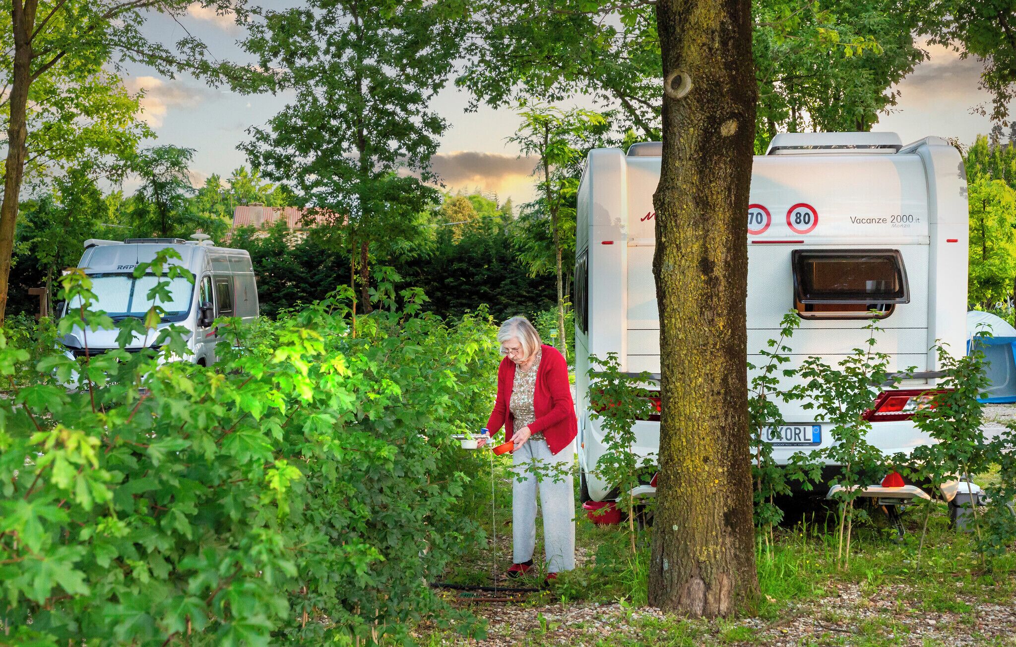 A campsite with RVs and a person tending to plants.