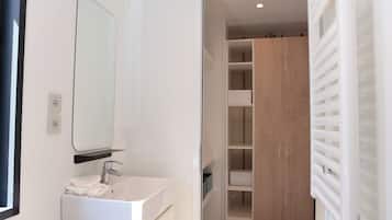 Un bany modern amb un lavabo blanc, un mirall i un armari de fusta amb nombroses prestatgeries.