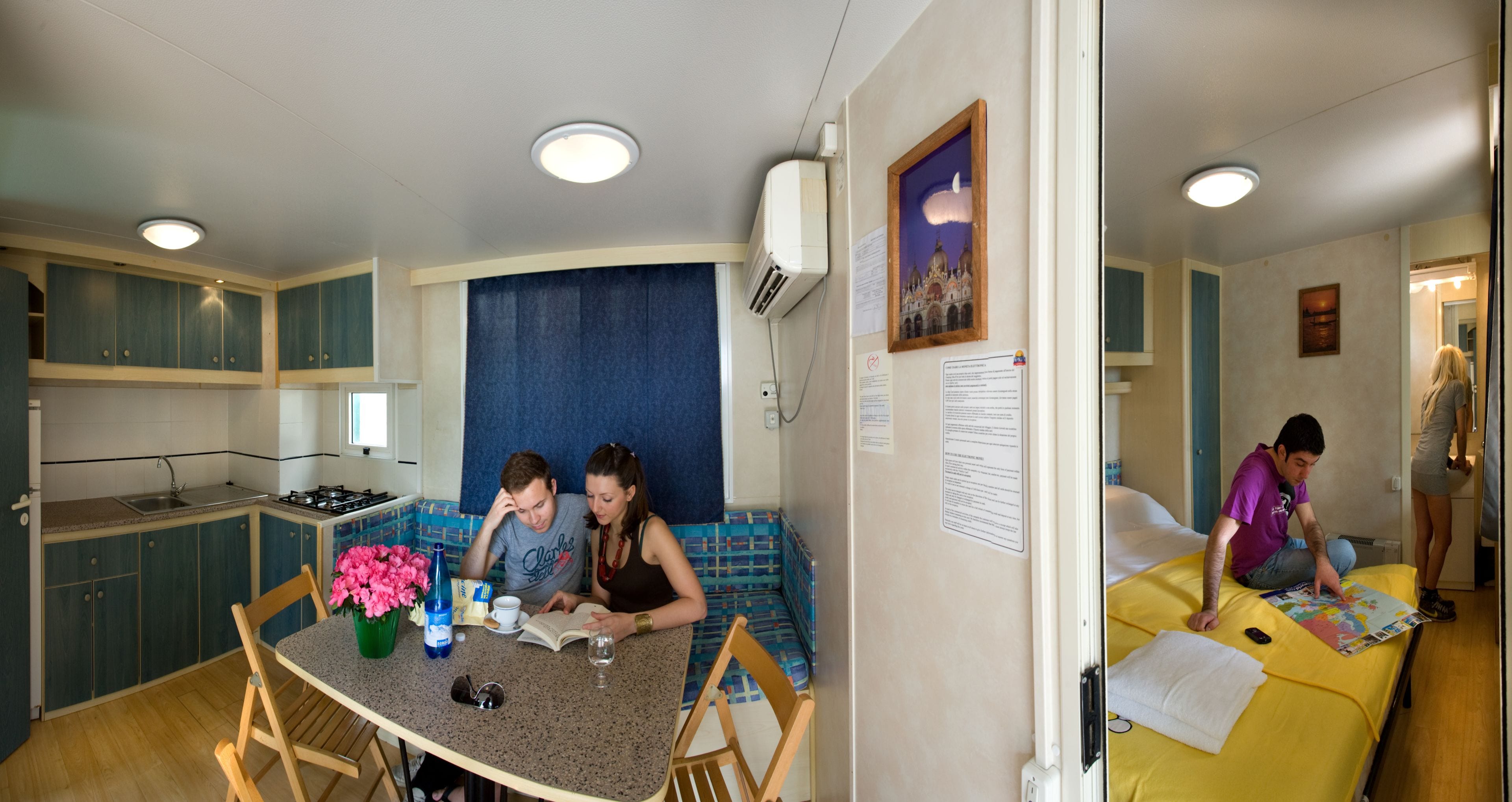 A compact kitchen with a dining area, a sofa, and a bed.