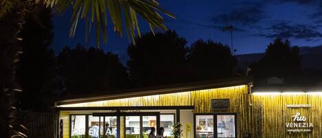 A hotel entrance with a glass door, a sign reading "Welcome to Hiu Venezia," and a well-lit exterior.
