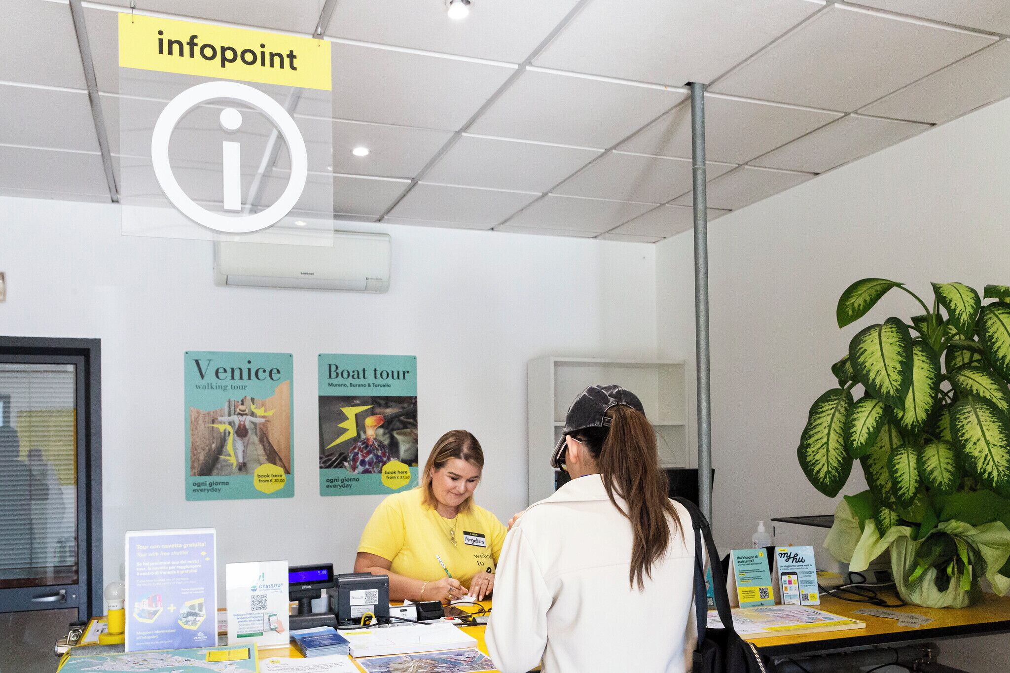 A reception desk with a large plant, informational posters, and a sign indicating 'infopoint'.
