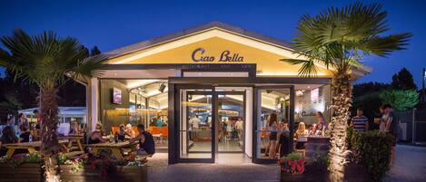 A restaurant with outdoor seating and a palm tree in the foreground.