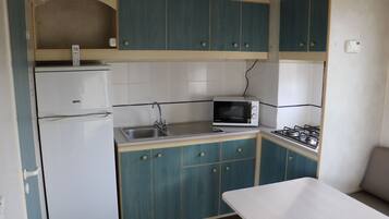A compact kitchenette with a refrigerator, microwave, sink, and stove.