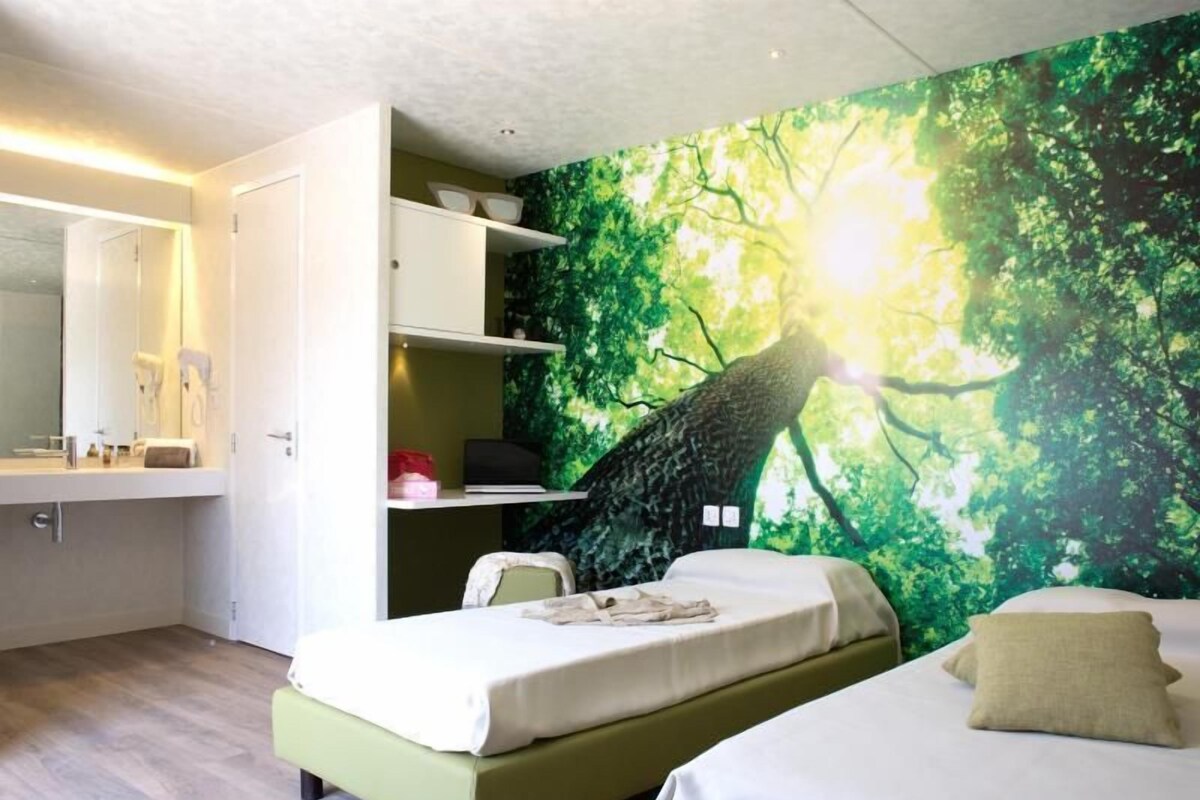 A bedroom with a bed, a nightstand, a wardrobe, and a wall mural.