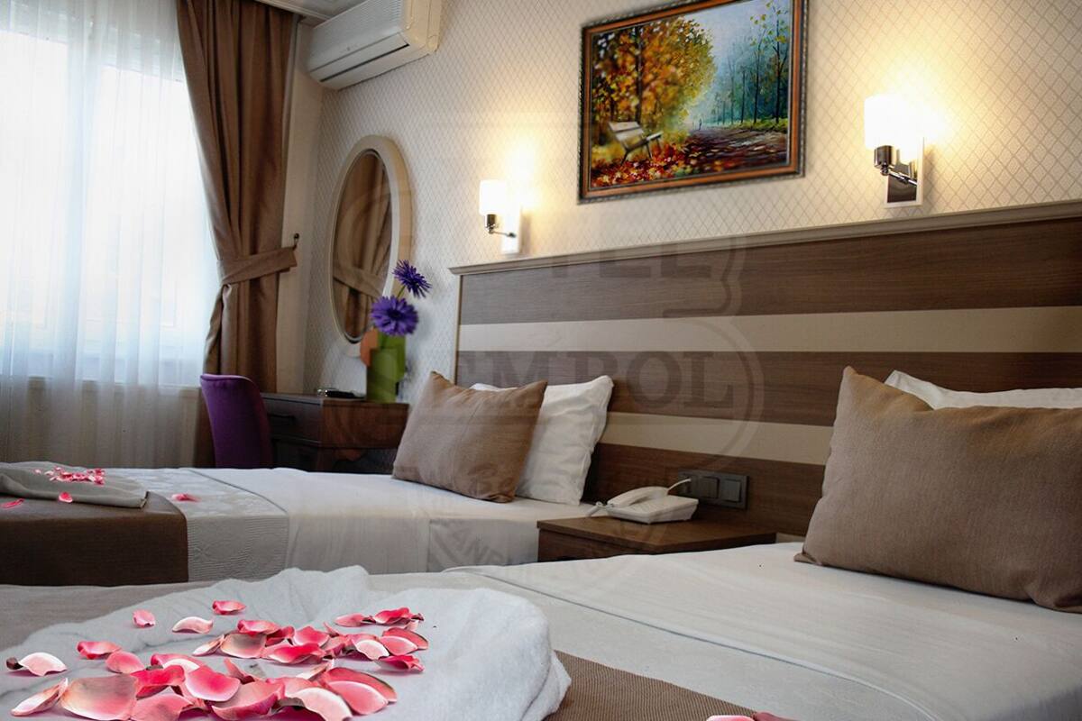 A hotel room with two beds, a painting on the wall, and a nightstand with a phone.