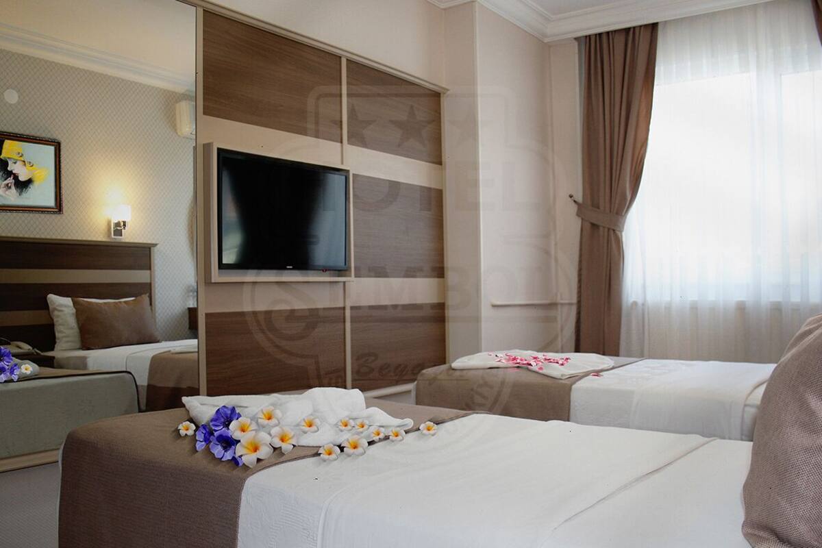 A hotel room with two beds, a TV, and a large window with curtains.