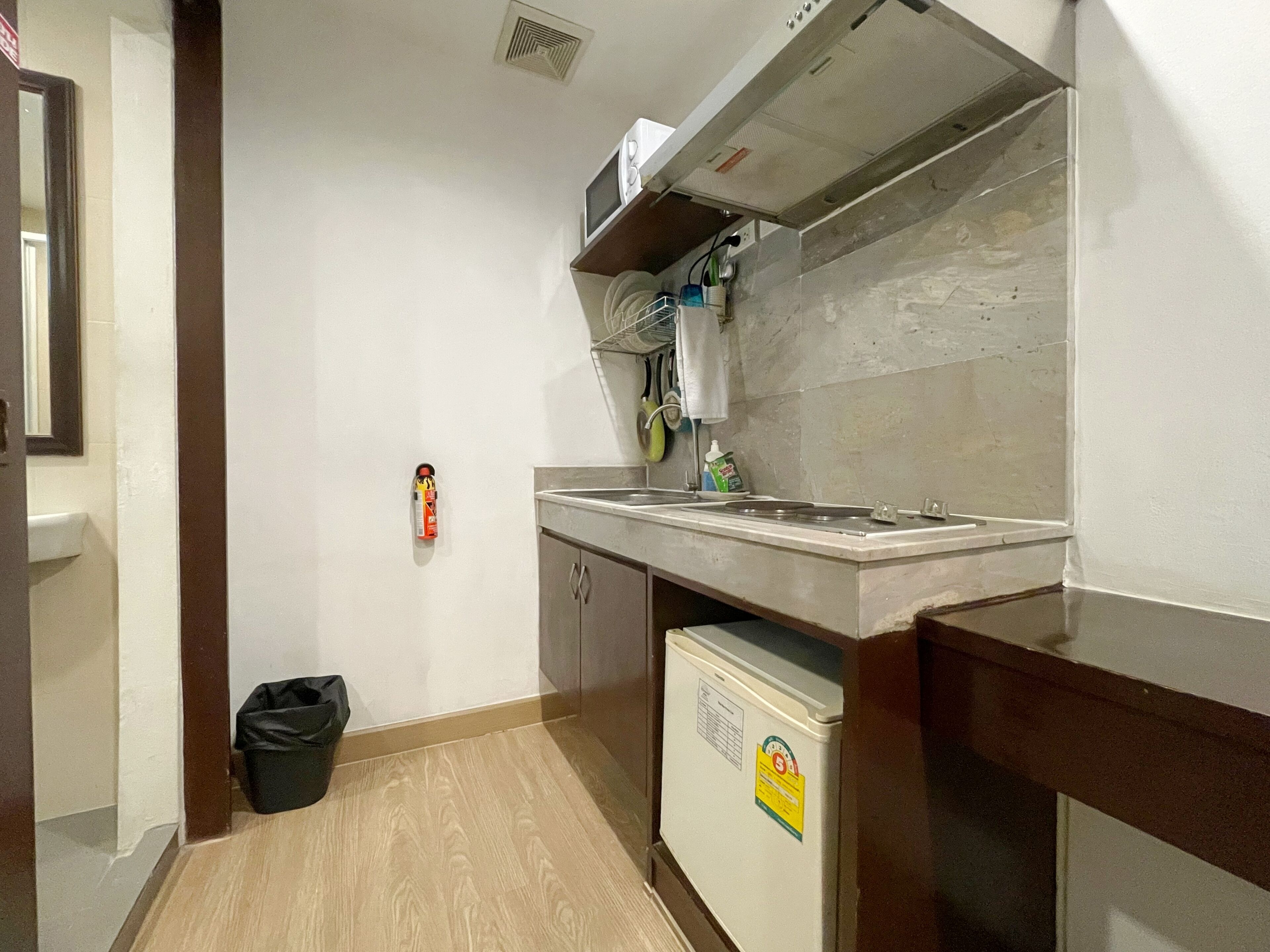A compact kitchen with a built-in stove, a small refrigerator, and a microwave.