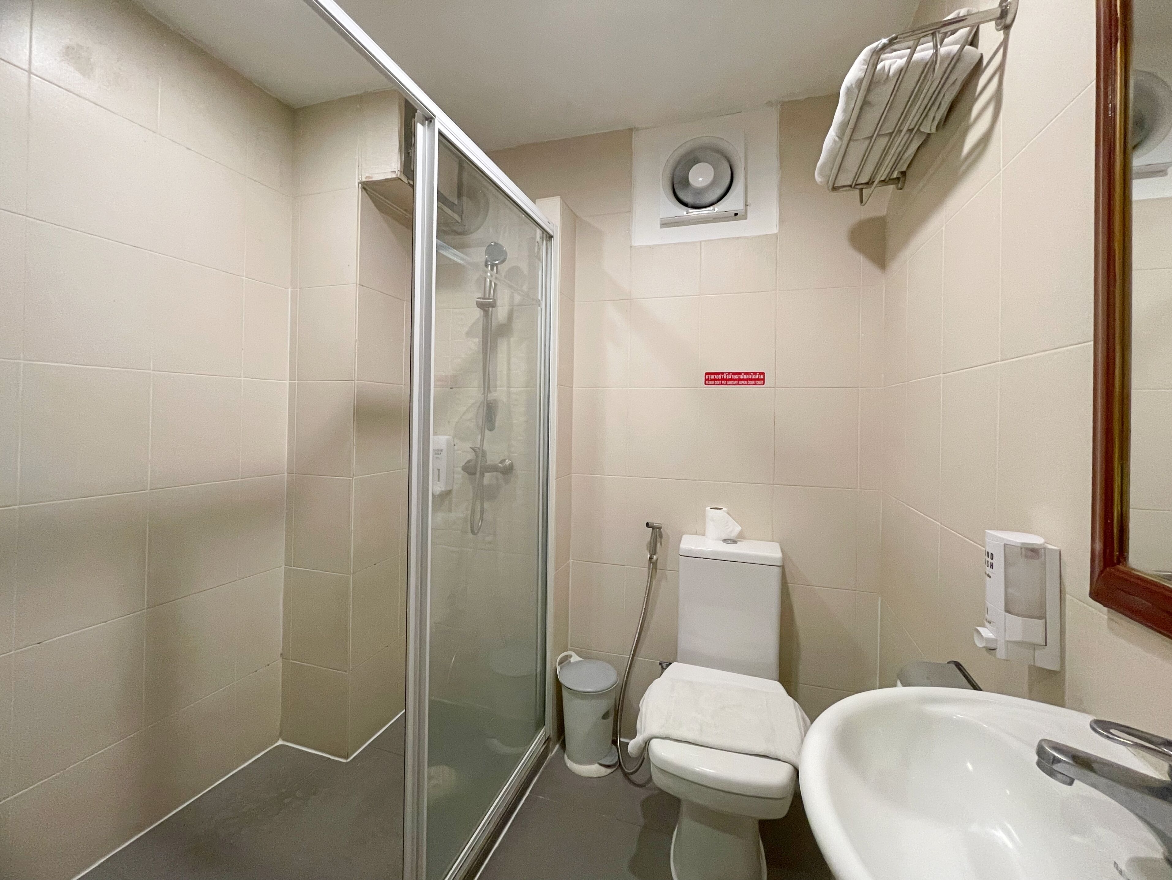 A bathroom with a glass shower enclosure, a toilet, a sink, and a towel rack.