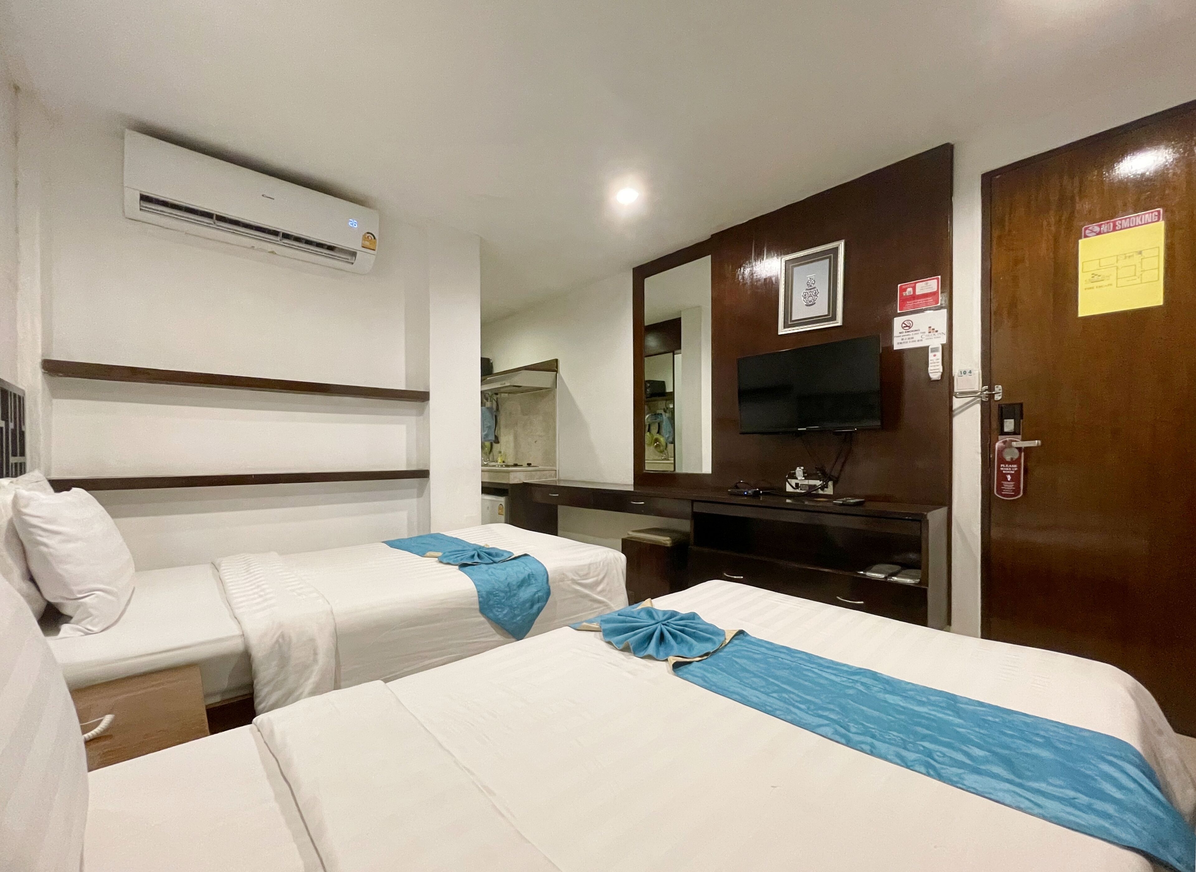 A hotel room with two beds, a TV, a mirror, a desk, and a wardrobe.