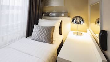 A hotel room with a bed, bedside table, lamp, and a mirror.