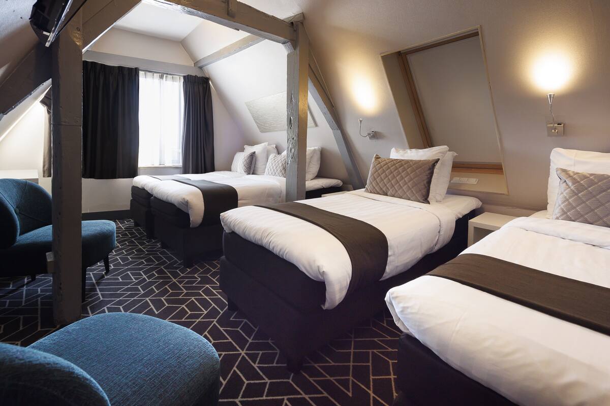 A hotel room with two beds, a desk, and a chair.
