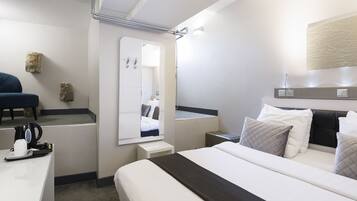 A modern hotel room with a bed, bedside table, and a mirror.