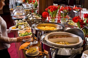 Montaje de bufé con diferentes opciones de comida, incluyendo un tazón de sopa, un plato de macarrones y una ensalada.