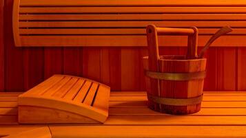 A wooden bench and a wooden bucket with a metal handle against a wooden wall.