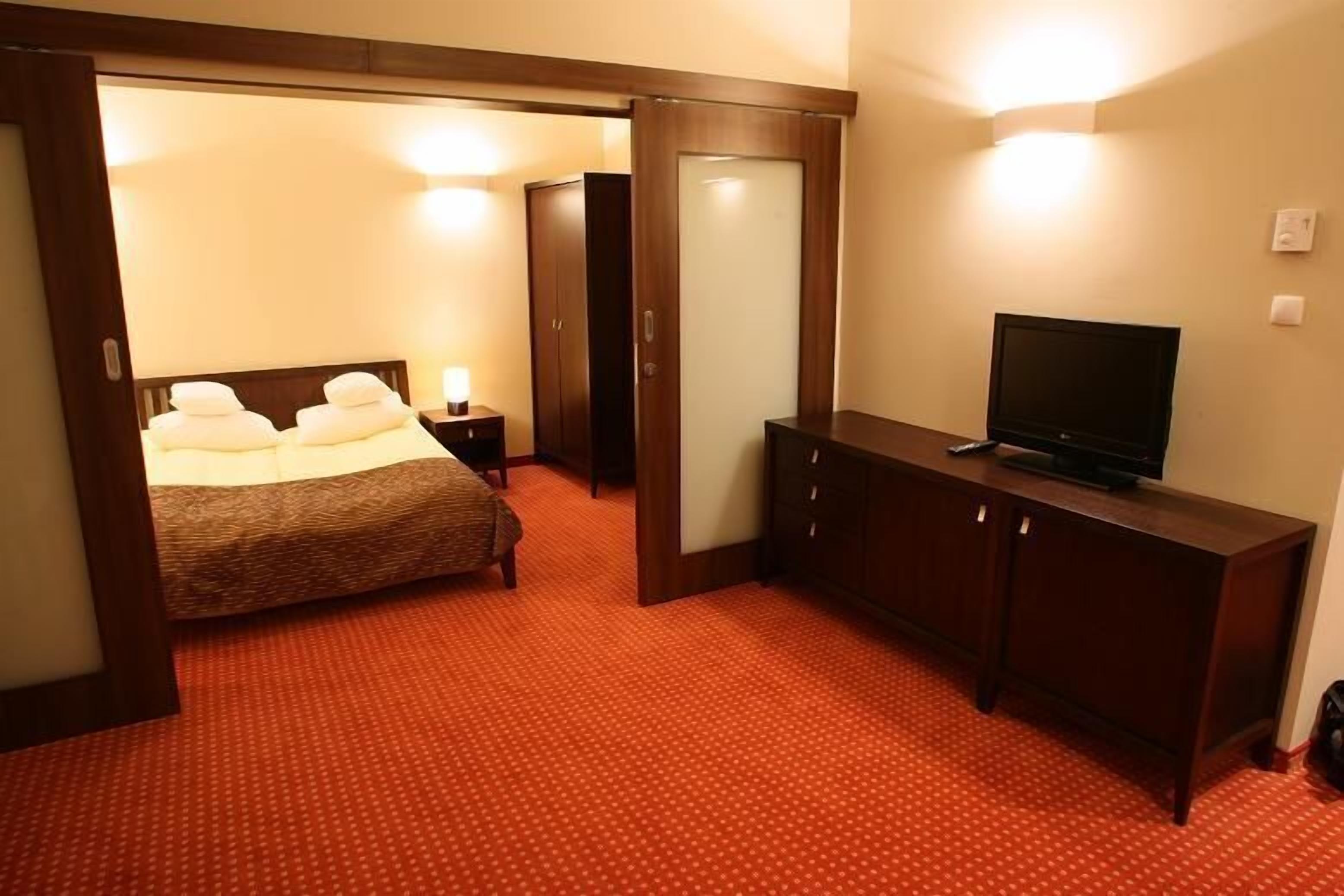 Ein Hotelzimmer mit Bett, Fernseher, Kleiderschrank und Spiegel.