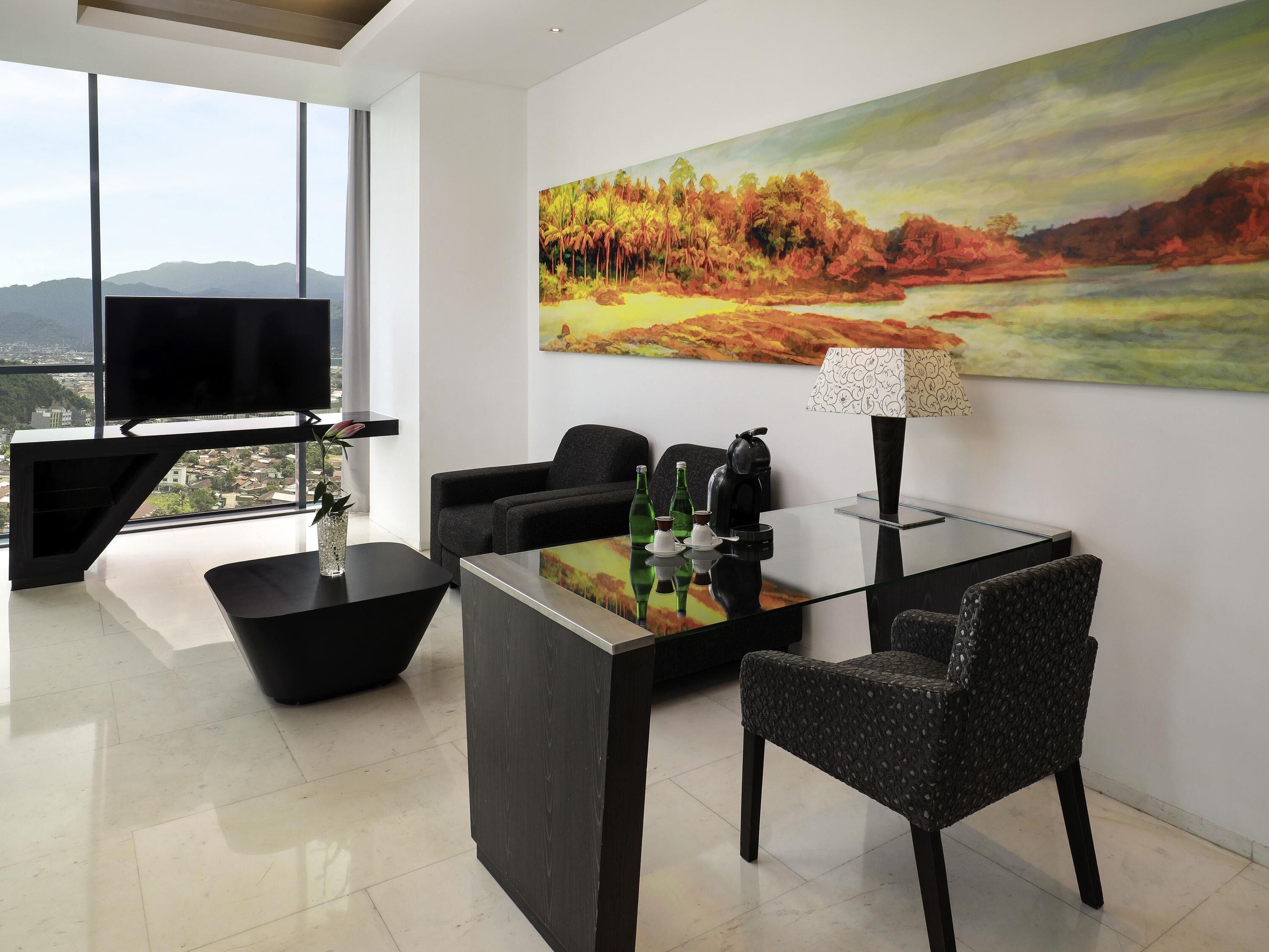 A modern living room with a large painting, a flat-screen TV, and a glass coffee table.