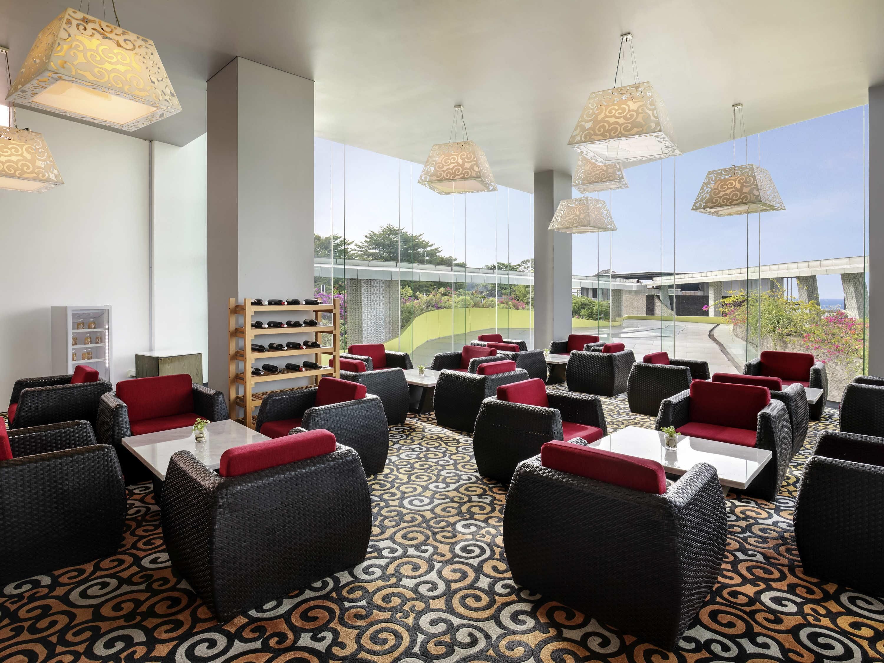 A restaurant with wicker furniture, red cushions, and patterned flooring.