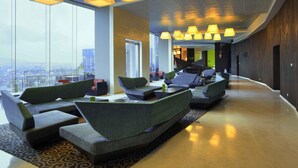 A modern lobby with seating, large windows, and hanging lamps. - Novotel Lampung (Bandar Lampung)