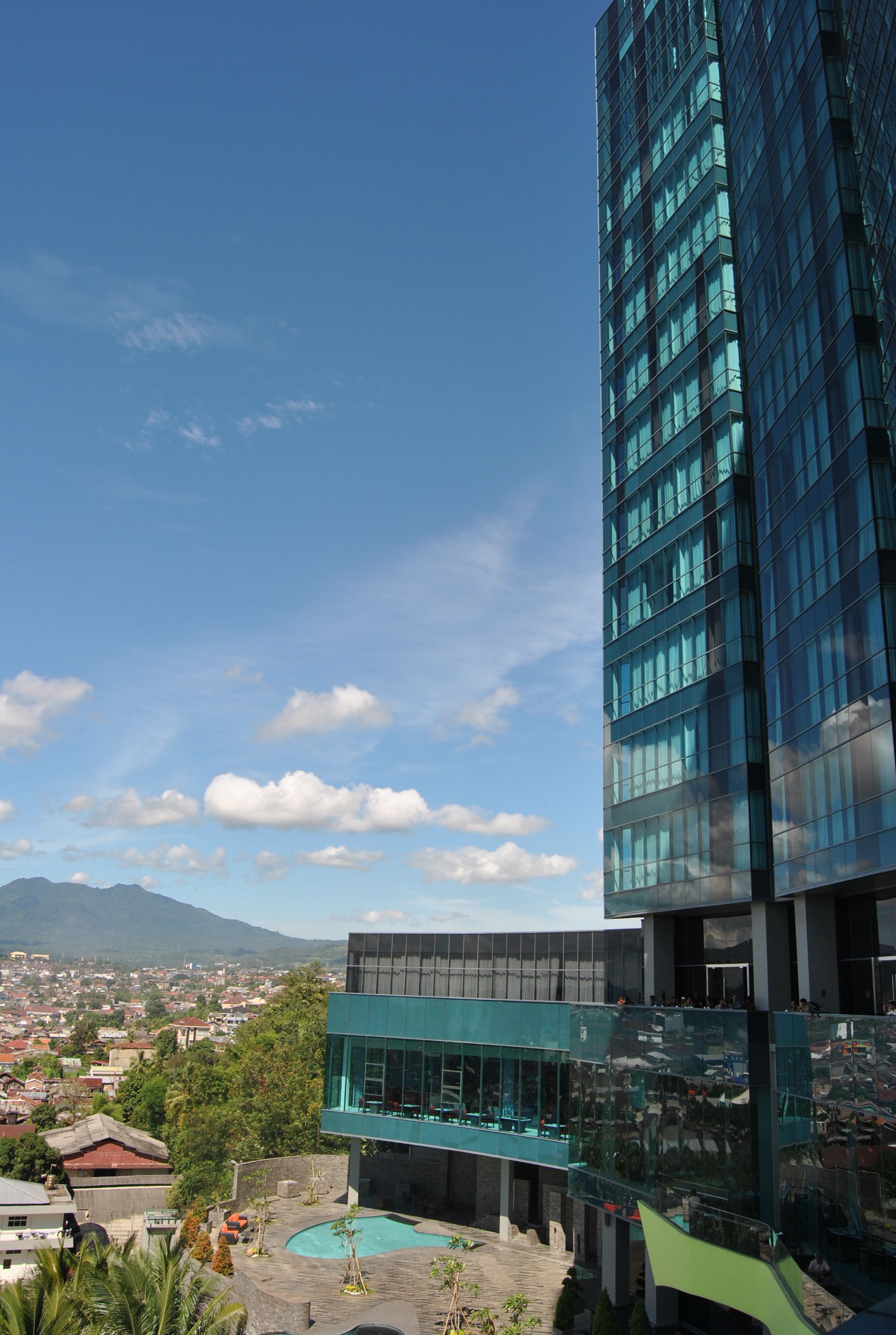 A modern building with large glass windows and a pool area.