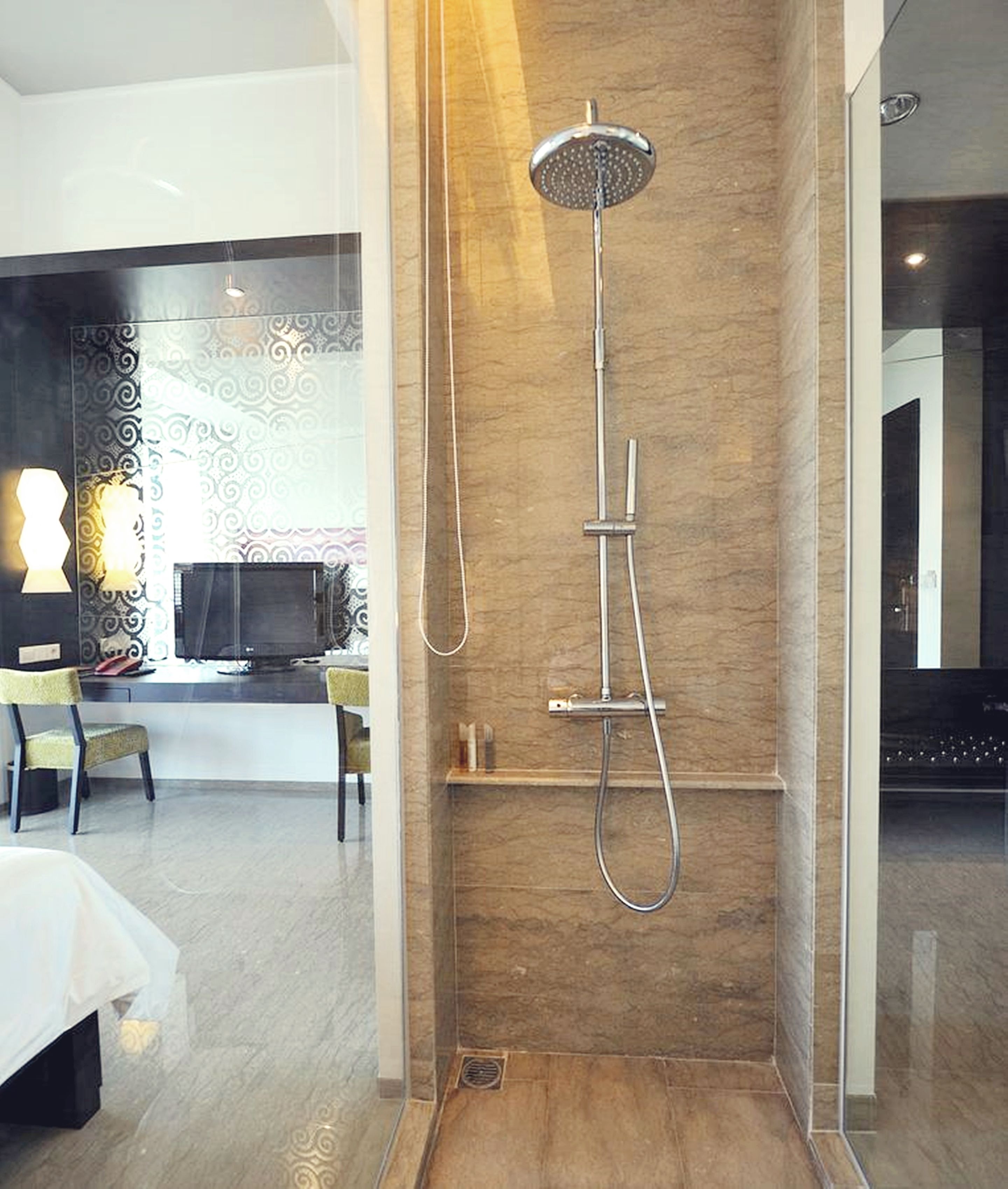 A modern bathroom with a shower, a vanity, and a seating area with chairs.