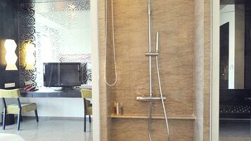 A modern bathroom with a shower, a vanity, and a seating area with chairs.