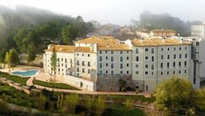 A hotel with multiple floors, a swimming pool, and a view of surrounding buildings and greenery. - Hotel Balneario Alhama de Aragon (Alhama de Aragon)