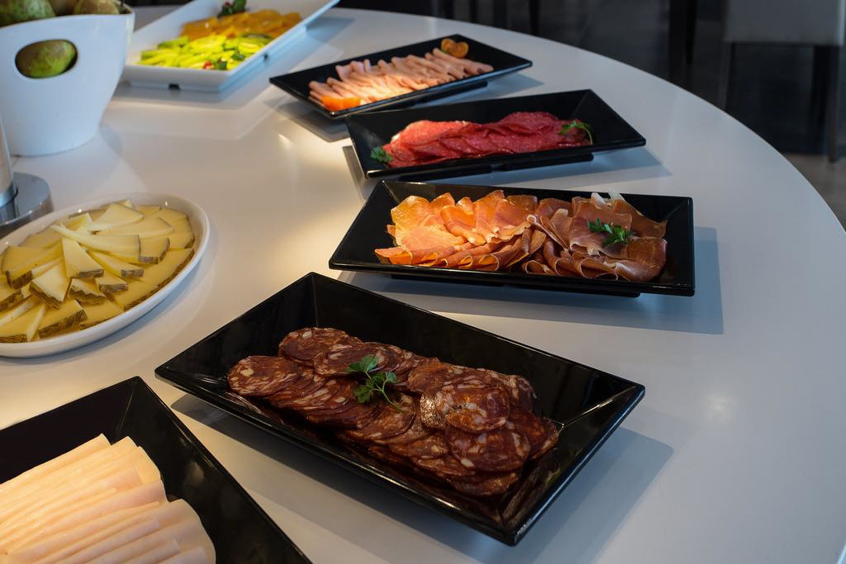 Una mesa con varios platos de comida, incluyendo fiambres y quesos.