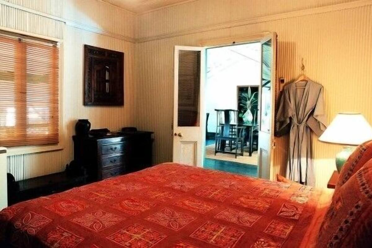 A hotel room with a bed, a dresser, a door leading to a balcony, and a coat rack.