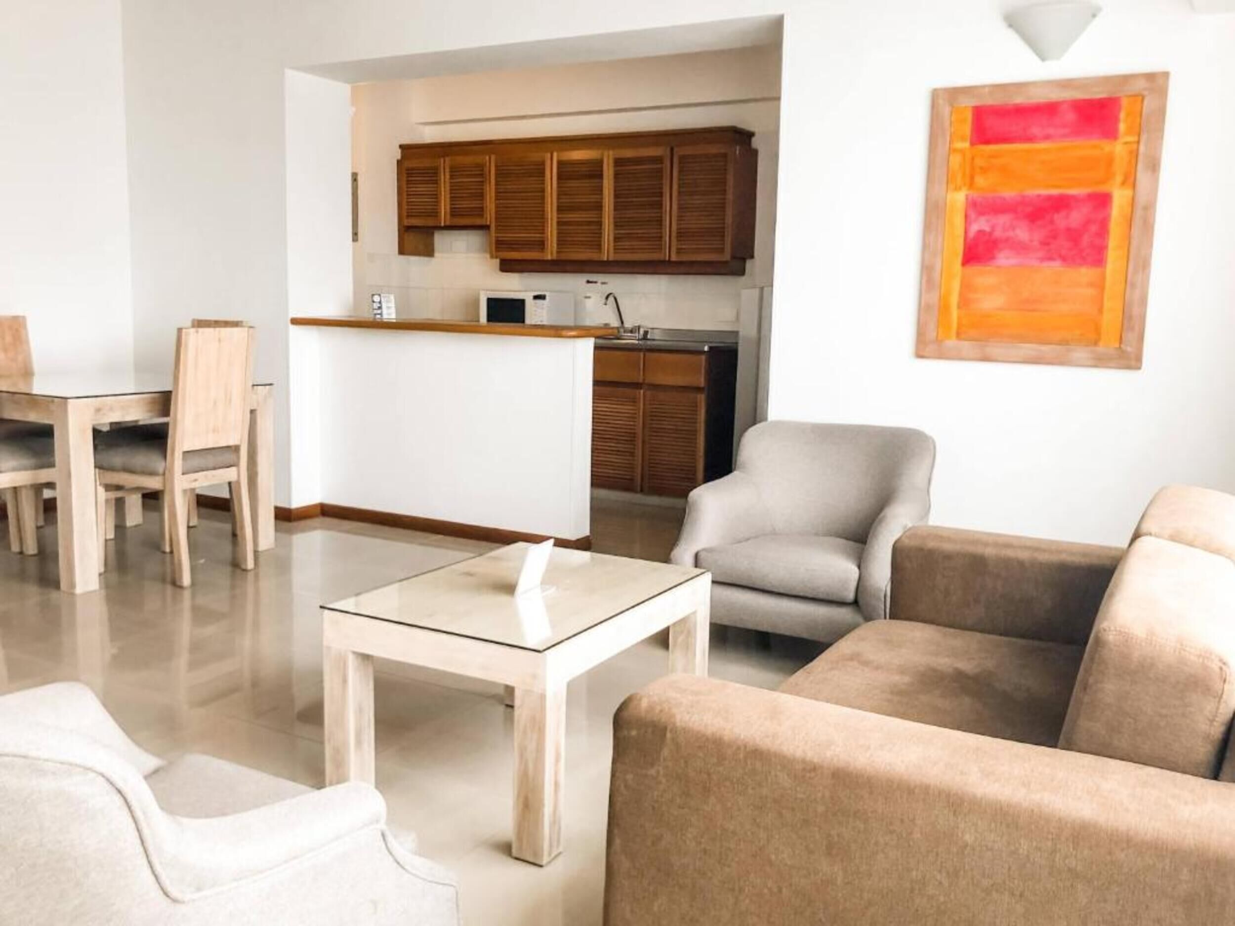 Uma sala de estar moderna com uma mesa de centro de vidro, sofá bege e uma área de jantar com cadeiras de madeira.