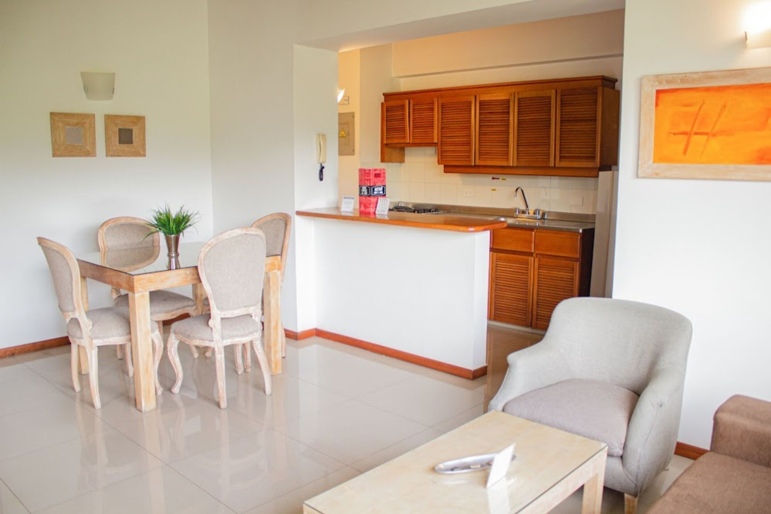 A modern kitchen with wooden cabinets, a central island, and a dining area with a table and chairs.
