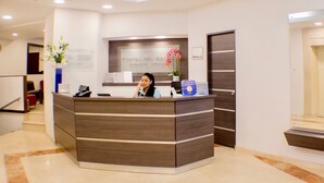 A reception desk with a sign reading "Portal De Rome Aparta Hotel".