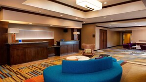 A hotel lobby with a reception desk, a blue sofa, and a patterned carpet.