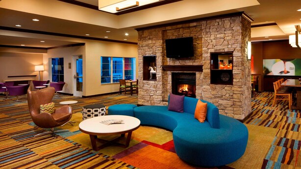 A modern lounge area with a stone fireplace, comfortable seating, and a flat-screen TV mounted on the wall.