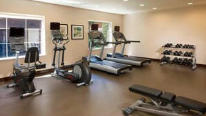 A gym with treadmills, elliptical machines, and dumbbells.