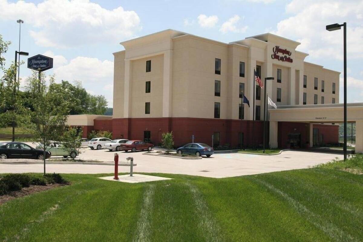 A Hampton Inn hotel with a parking lot, a lawn, and a clear sky.