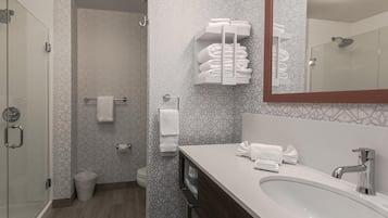 A modern bathroom with a glass shower enclosure, a white sink with a mirror, and a towel rack with neatly folded towels.