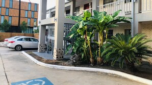 A modern building with a covered entrance, a parking area, and a wheelchair-accessible ramp. - Summit Inn - Houston Medical Center (Houston)